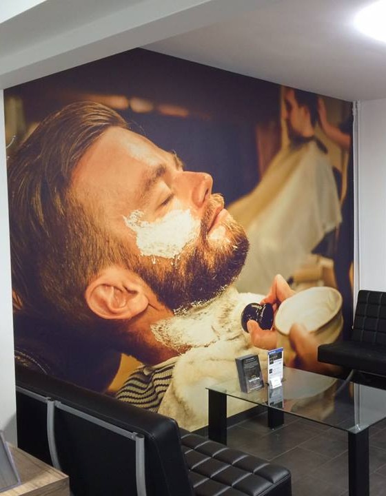 De wachthoek met zwarte leren banken en een grote muurschildering van een man die geschoren wordt